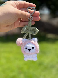 a crocheted llama keychain with a pink bow
